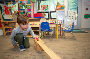 little boy playing with car on track in PreK