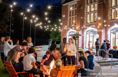 A photo of students at a boarding school enjoying residential life, toasting s'mores outside under twinkle lights