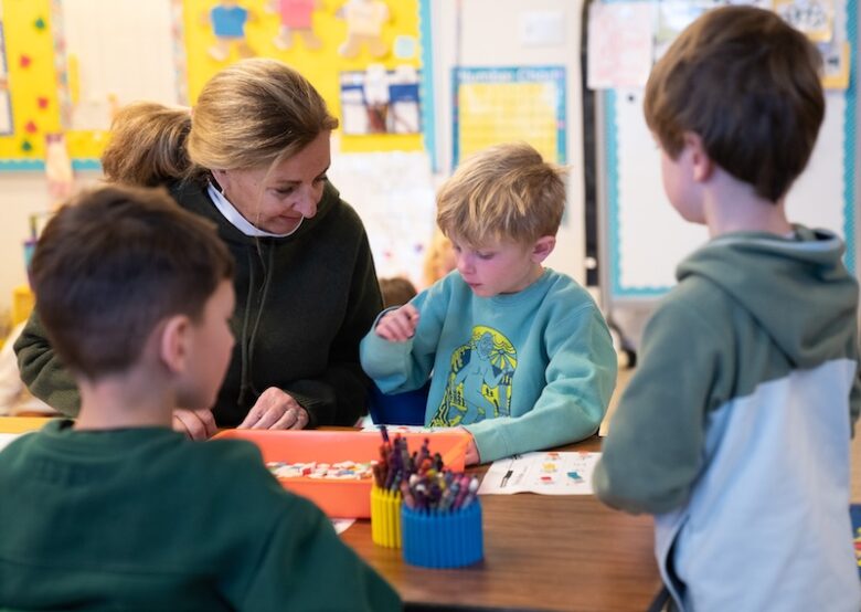 A Kindergarten teacher helps students build their reading skills at a table at Aspen Country Day School, a PreK to Eighth Grade independent school in Colorado.