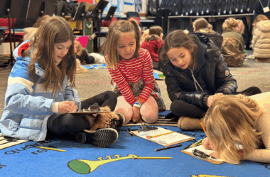 Students talking together on a blue carpet in music class at Aspen Country Day School in Colorado
